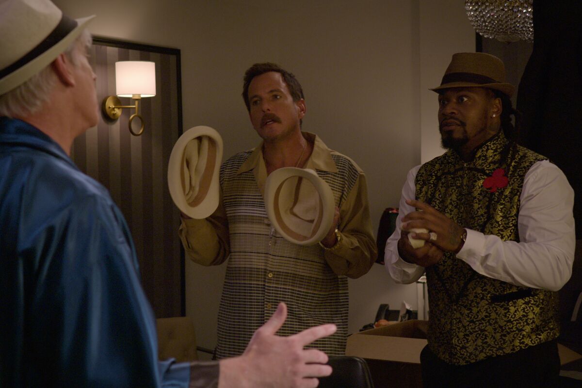 Two men confront a man in a hat.
