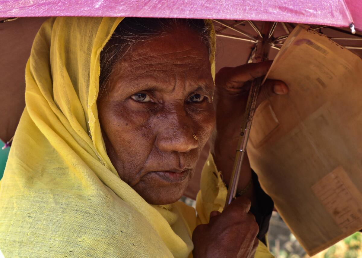 A Rohingya refugee woman waits to collect food aid at the Kutupalong refugee camp in Bangladesh.