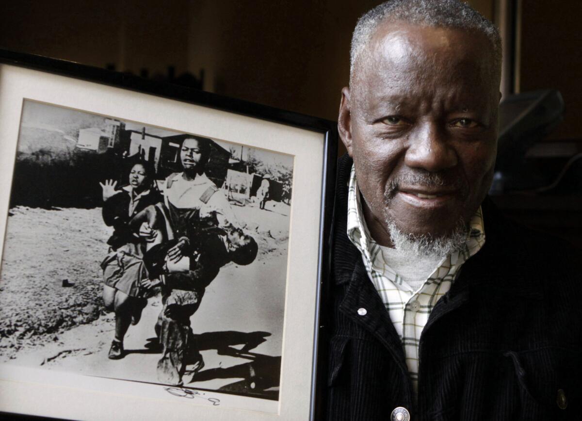 South African photographer Sam Nzima poses with his iconic photo in 2011.