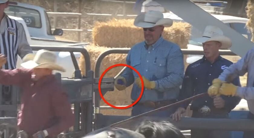 A still image from a video taken at the Poway Rodeo in 2018 shows workers holding pronged devices near horses.
