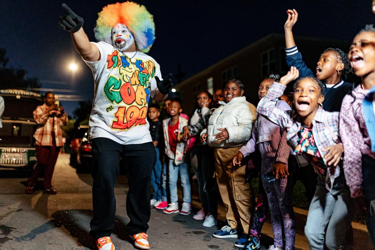A clown points with kids in the background.