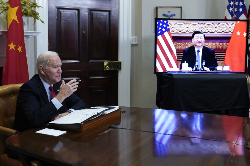 President Biden at a desk, Chinese President Xi Jinping on video screen 