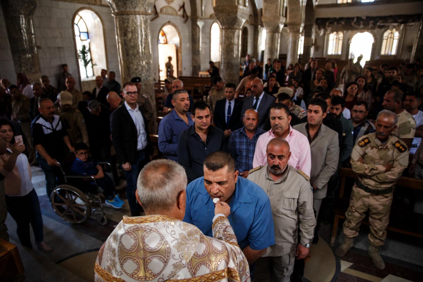 The congregation lines up to receive the holy communion from Abusharnad Alisoo during Easter Mass at the Mary Yohanna Church, damaged in the war when Iraqi forces liberated the city from Islamic State in Qaraqosh, Iraq.
