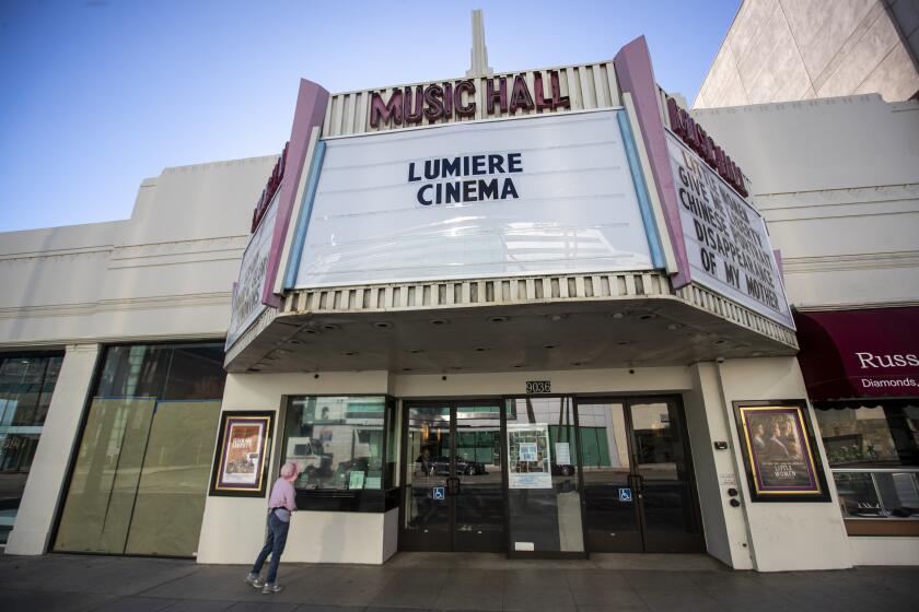 BEVERLY HILLS, CALIF. -- TUESDAY, DECEMBER 31, 2019: A person views the exterior of the Lumiere Cinema at the Music Hall in Beverly Hills, Calif., on Dec. 31, 2019. Co-owners Peter Ambrosio, Lauren Brown and Luis Orellana, longtime Laemmle staffers, film fans and self-described “Los Angeles ‘film people,’” worked together at the Music Hall in Beverly Hills for five years. When there were rumors the theater might close, the trio hatched a plan and the Lumiere Cinema at the Music Hall was born. Now, they face the challenge of keeping an independent neighborhood art house alive in the age of Netflix and Disney blockbusters dominating the cinematic landscape. (Allen J. Schaben / Los Angeles Times)