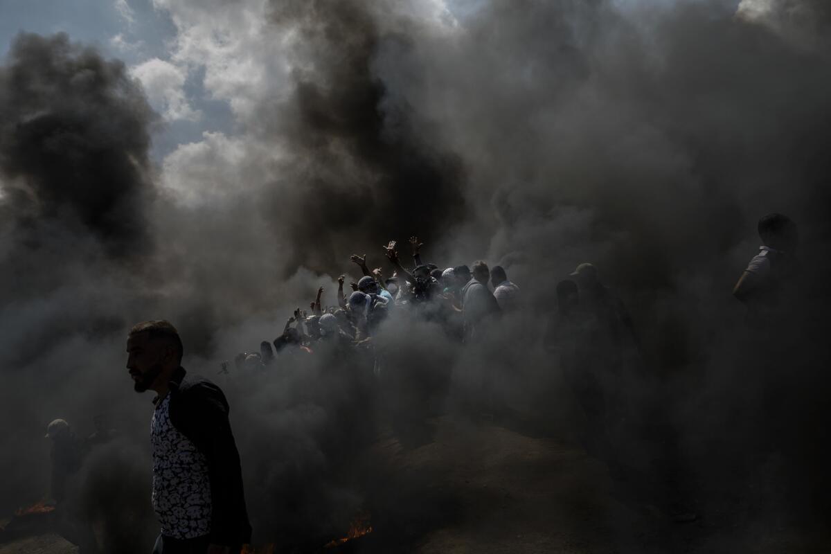 Palestinians cheer and chant as they burn tires at the border fence separating Israel and Gaza in a camp east of Gaza City.