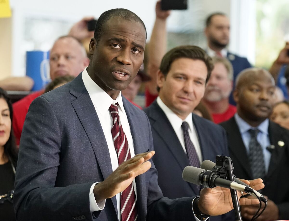 FILE - Florida Surgeon General Dr. Joseph Ladapo, front left, gestures as speaks to supporters and members of the media before a bill signing by Gov. Ron DeSantis, front right, Nov. 18, 2021, in Brandon, Fla. Florida health officials have asked the state medical board to draft new policies that would likely restrict gender dysphoria treatments for transgender youth. (AP Photo/Chris O'Meara, File)