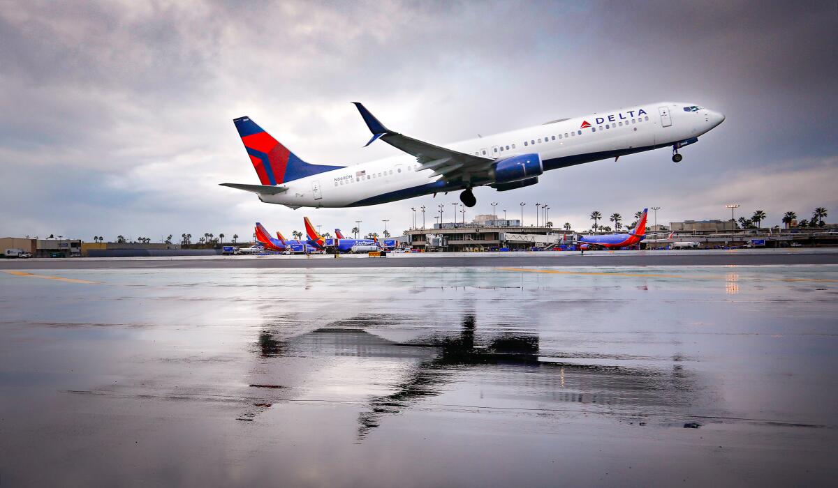 A Delta Airlines Boeing 737 is reflected in water while taking off from San Diego International Airport