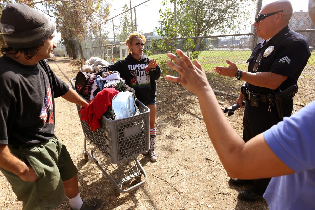 LAPD Officer Austin Fernald talks with Veronica Gonzalez and Miguel Angel Gonzalez along the Arroyo Seco Parkway during a sweep of homeless encampments in June.