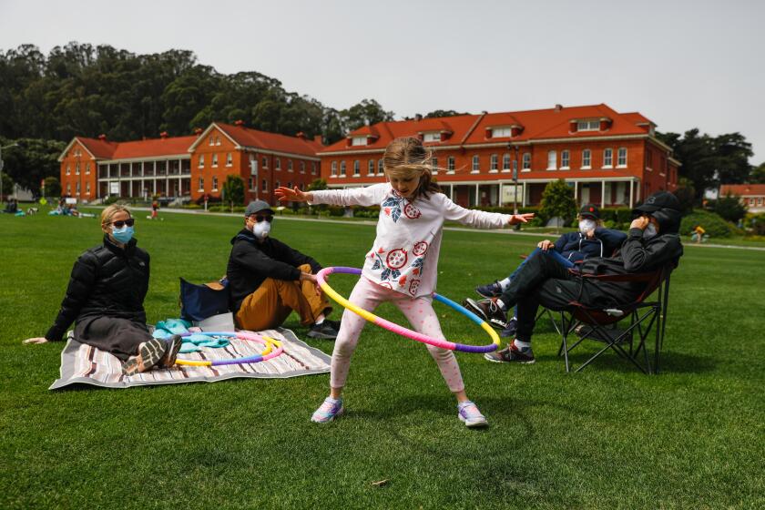 SAN FRANCISCO, CA - APRIL 26: Angie Muscat (center), 6, hula hoops as mom Christina Dam (left), dad Jason Muscat (second from left), grandmother Becky Muscat (second from right) and grandfather Bob Muscat (right) look on at the Main Parade Grounds in the Presidio in San Francisco, California on Sunday, April 26, 2020. Public health officials had feared spring-like weather over the weekend would cause a rush of people to set aside shelter in place mandates and descend upon public parks and beaches, putting themselves at risk to coronavirus exposure.(Gabrielle Lurie/The San Francisco Chronicle via Getty Images)