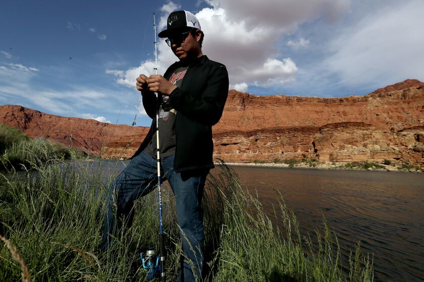 MARBLE CANYON, AZ. - DEC 24, 2021. A fisherman sets up on the banks of the Colorado River as it cuts through the Navajo Nation en route to the Grand Canyon. This segment of the river joins two vast reservors: Lake Powell in Utah and Lake Mead in Nevada. (Luis Sinco / Los Angeles Times)