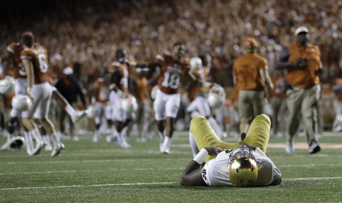 A Notre Dame player lies on the turf as Texas celebrates their win in double overtime in Austin, Texas.