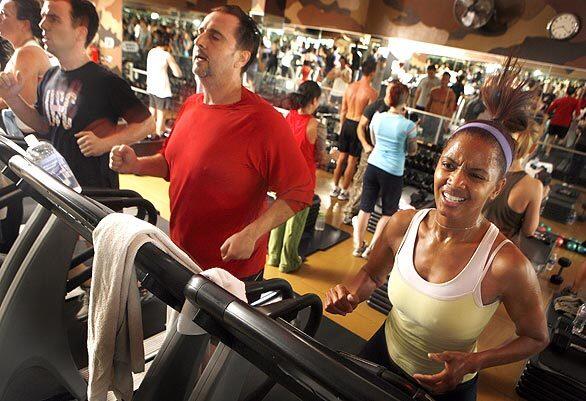 Sean Bello, center, and Rhonda Smith, right, push themselves on the treadmill while others behind them work out with exercises on the floor at Barry's Boootcamp in West Hollywood. The boot camp programs at Barry's and other gyms help people to kick start their New Year's fitness programs.