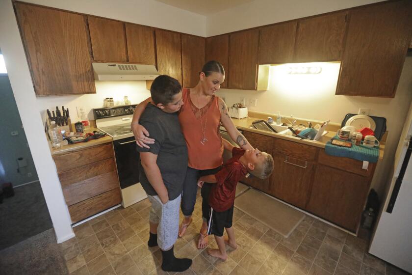 Misty Dotson hugs her son's at their home Tuesday, Aug. 20, 2019, in Murray, Utah. Dotson is a 33-year-old single mother of two boys, ages 12 and 6, who goes to Planned Parenthood for care through the Title X program. Dotson is among the 39,000 people received treatment from Planned Parenthood of Utah in 2018 under a federal family planning program called Title X. The organization this week announced it is pulling out program rather than abide by a new Trump administration rule prohibiting clinics from referring women for abortions. (AP Photo/Rick Bowmer)