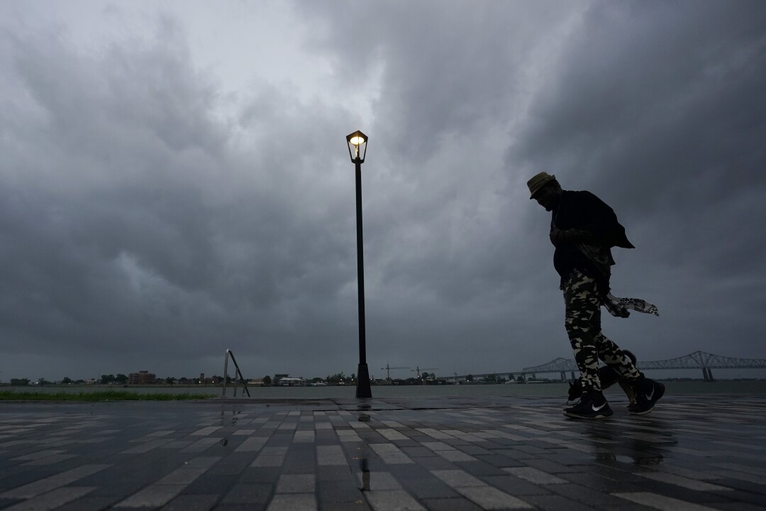 A man walks by a river in the rain.