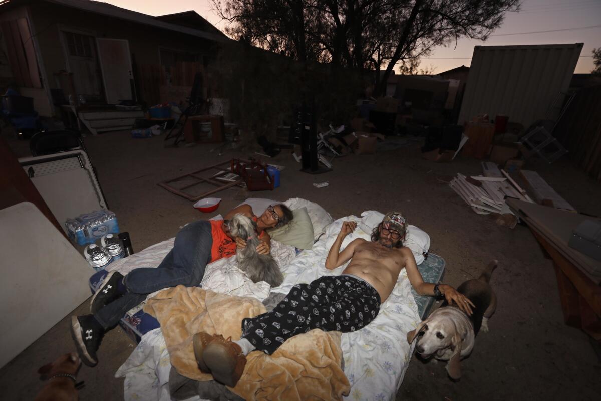 Ronnie Tolbert, left, and her husband, Dan, sleep on a pair of mattresses in front of their earthquake damaged home in Trona.