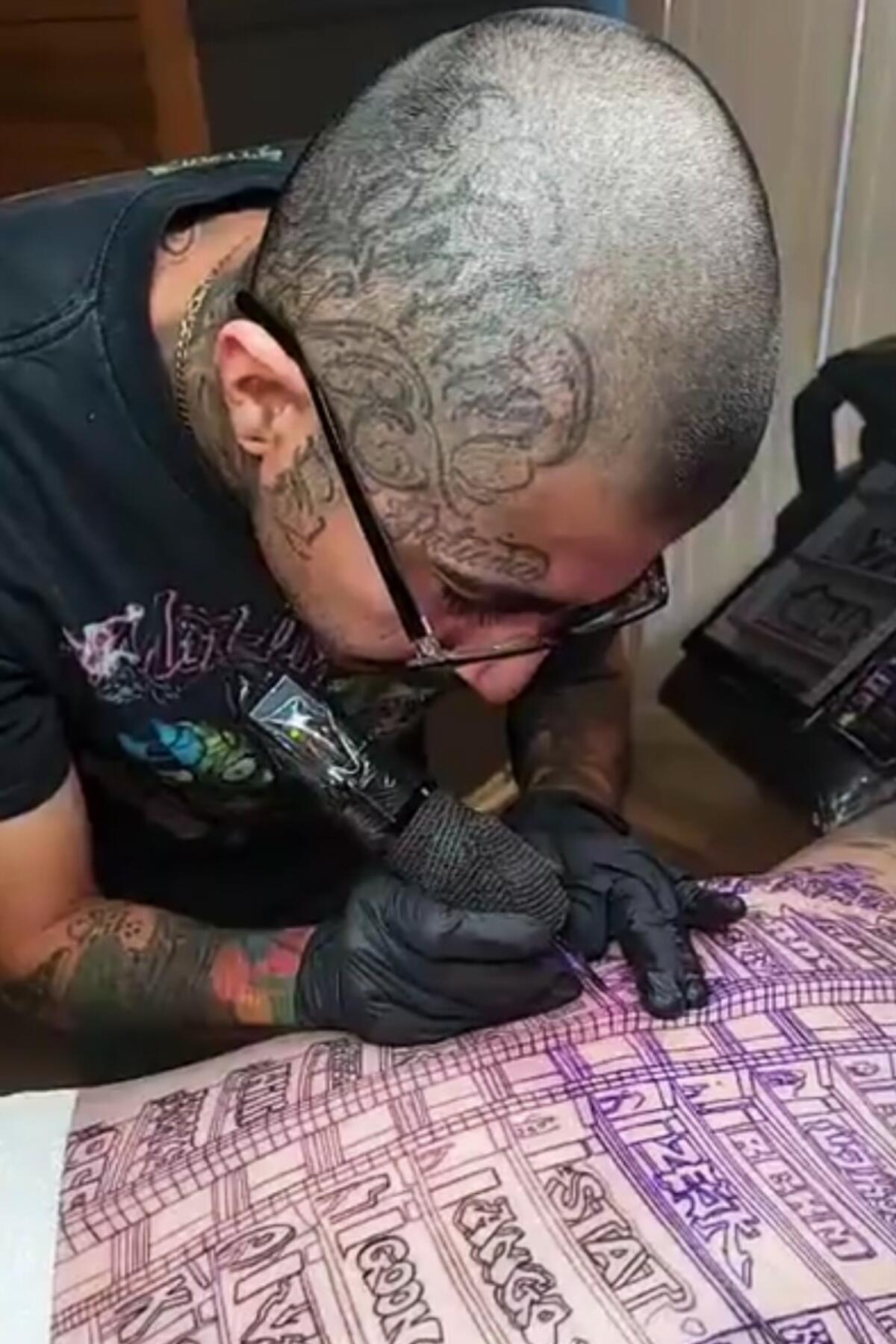 Tattoo artist Eric Reyna works on a tattoo that features the graffiti-covered Oceanwide Plaza.