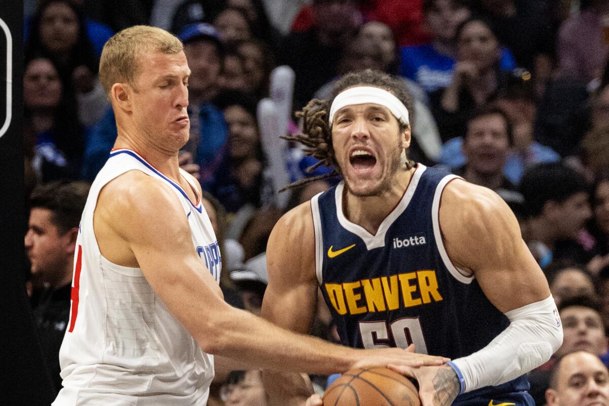 Clippers center Mason Plumlee tries to bat the ball out of Denver Nuggets forward Aaron Gordon's hands.