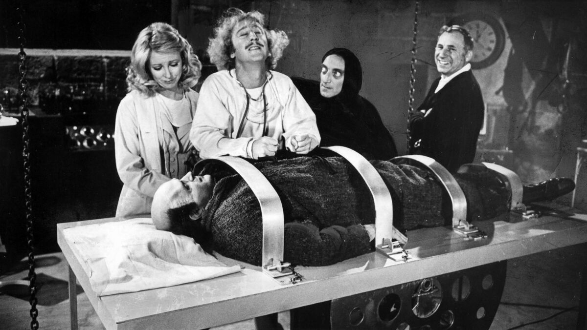 March 27, 1974: Director Mel Brooks, right, looks on as Teri Garr, Gene Wilder, Marty Feldman, from left, and Peter Boyle as the monster, re-create a scene from the movie "Young Frankenstein."