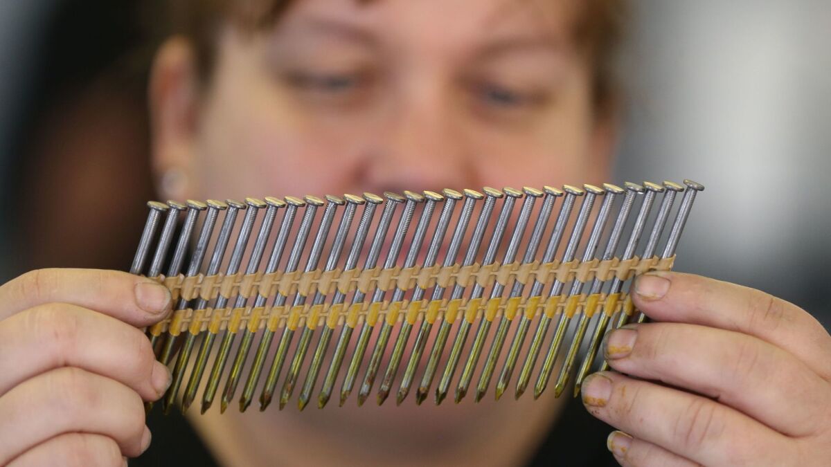 A worker at Mid Continent Nail Corp. looks at a set of nails at the company' production factory in Missouri.