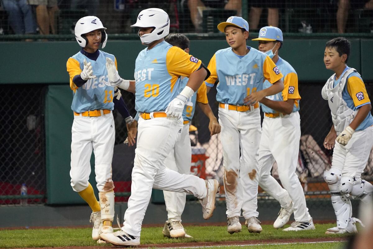 Honolulu's Esaiah Wong (20) is greeted by his teammate along the third base line as he heads home on his home run off of Massapequa, N.Y.'s Lucas Mininni during the fifth inning of a baseball game at the Little League World Series in South Williamsport, Pa., Friday, Aug. 19, 2022. (AP Photo/Tom E. Puskar)