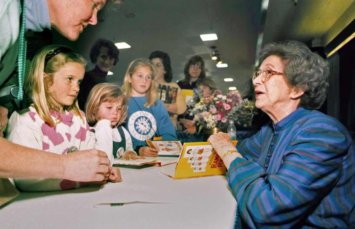 Beverly Cleary sits at a book-signing table crowded with young girls and their parents.