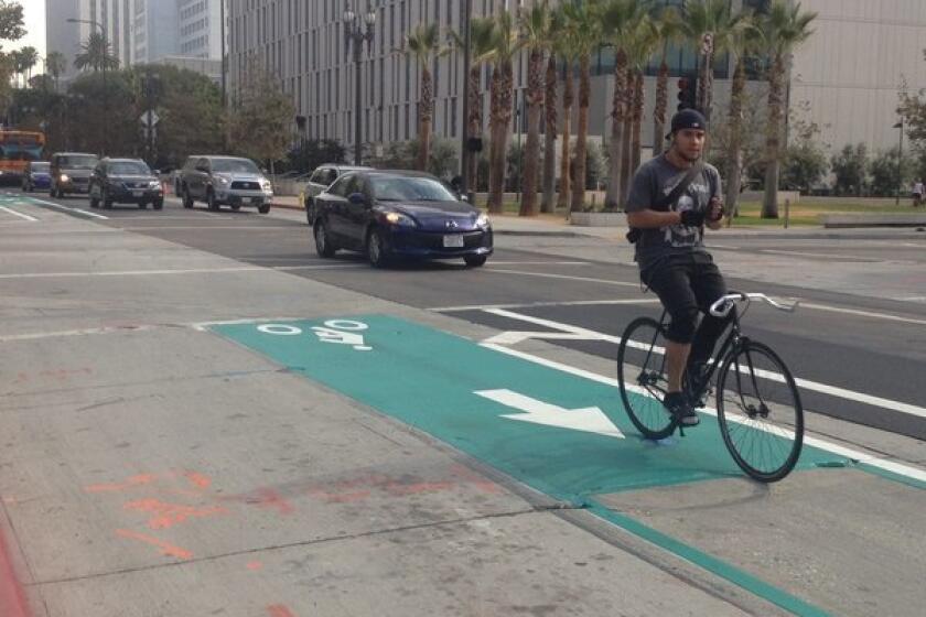 A bicyclist rides the new darker green bike lane on Spring Street south of 2nd Street in downtown Los Angeles.