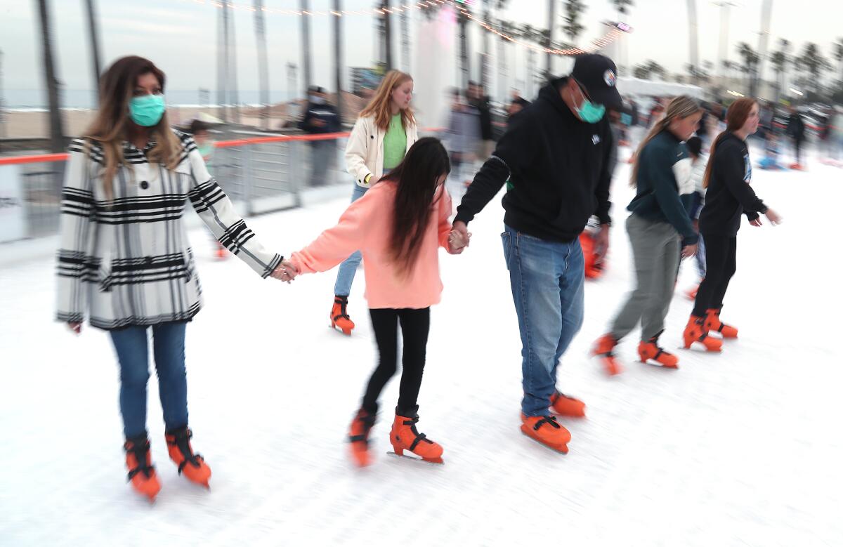 A family holds hands as they round a turn during the "Skate With HBPD" event at the Surf City Winter Wonderland.