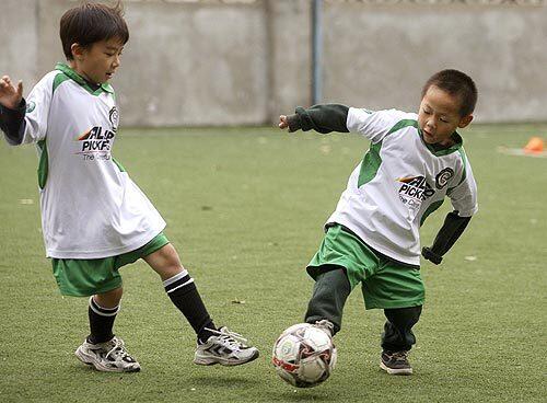 Levi, right, plays soccer at his school in Beijing.