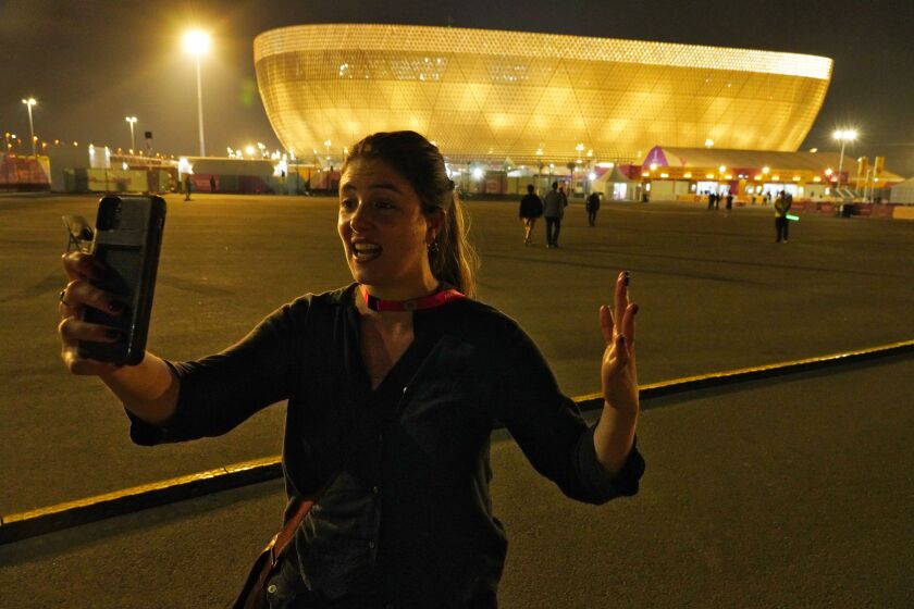 Associated Press correspondent Isabel DeBre films a selfie video in front of Lusail Stadium in Lusail, Qatar, Sunday, Nov. 20, 2022. With Qatar's World Cup the most compact tournament in the competition's history, DeBre set out to see four matches in one day. (AP Photo/Jon Gambrell)