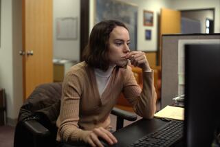 A woman leans over her desk toward her computer