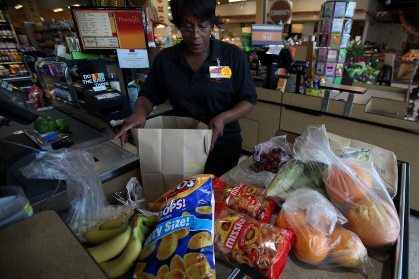 Cashier Sheila Curl bags groceries into a paper bag at Fresco Community Market in Los Angeles.