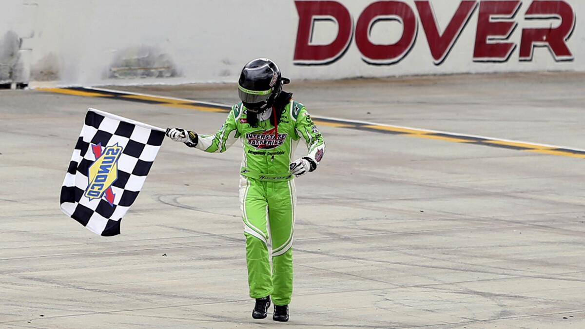 NASCAR driver Daniel Suarez takes a victory lap with the checkered flag Sunday after winning the Xfinity Series race at Dover.