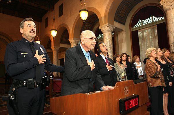 Retired LAPD Deputy Chief George Beck leads the pledge of allegiance for the opening of the Los Angeles City Council meeting with his son, LAPD Deputy Chief Charlie Beck, and Los Angeles Mayor Antonio Villaraigosa at his side. After a confirmation meeting with questions and answers, the council unanimously confirmed Beck to head the LAPD.