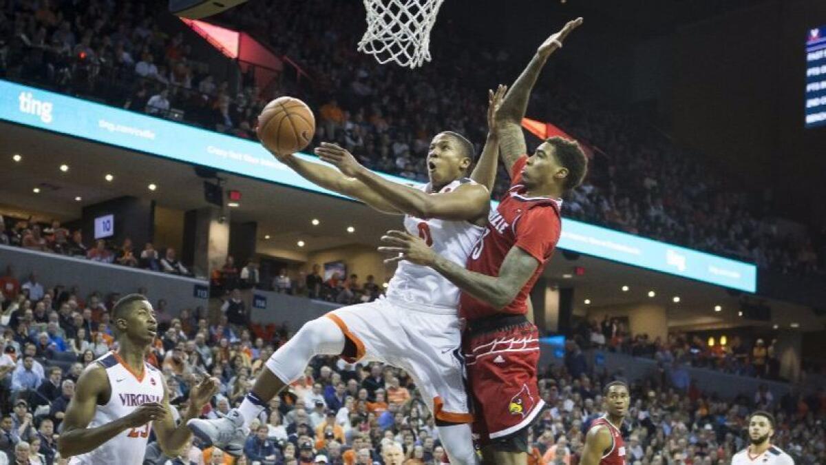 Virginia's Devon Hall (0) goes past Louisville defender Ray Spalding (13) for a basket on Feb. 6.