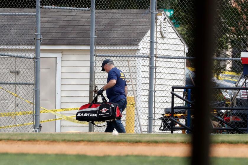 An FBI investigator removes a baseball bag from the first base side dugout on the baseball field in Alexandria, Va., Wednesday, June 14, 2017, that was the scene of a shooting involving House Majority Whip Steve Scalise of L.a, and others, during a congressional baseball practice. (AP Photo/Alex Brandon)