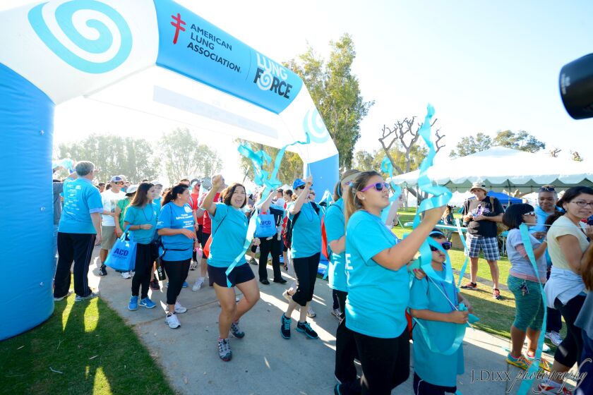 a group of people walk during a 5k event wearing bright blue shirts