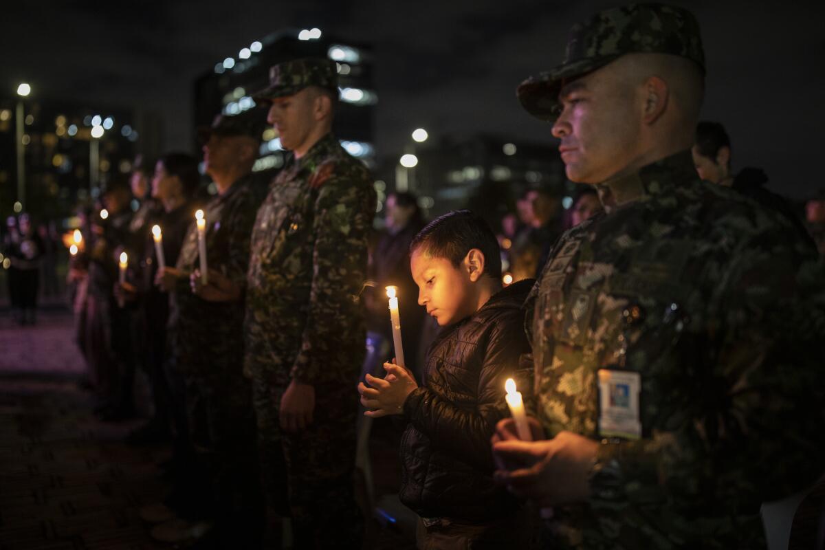 Un niño sostiene una vela durante una vigilia en honor de soldados muertos en un ataque reciente