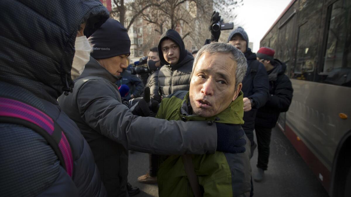 Plainclothes security officials take away a supporter of Chinese human rights lawyer Wang Quanzhang near the Secondary Intermediate People's Court of Tianjin on Dec. 26.