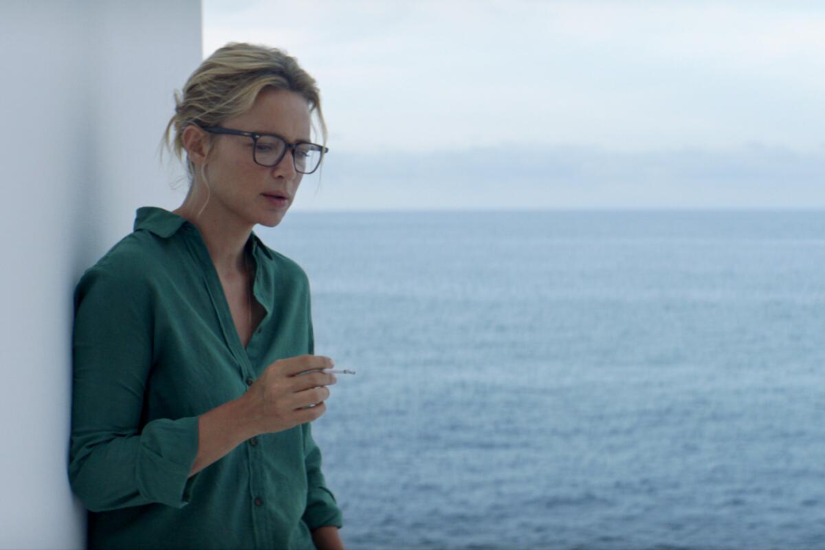 Sybil, played by Virginie Efira, smokes in front of the sea.