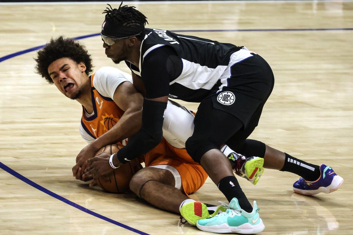 Clippers guard Reggie Jackson, top, ties up Suns forward Cameron Johnson.