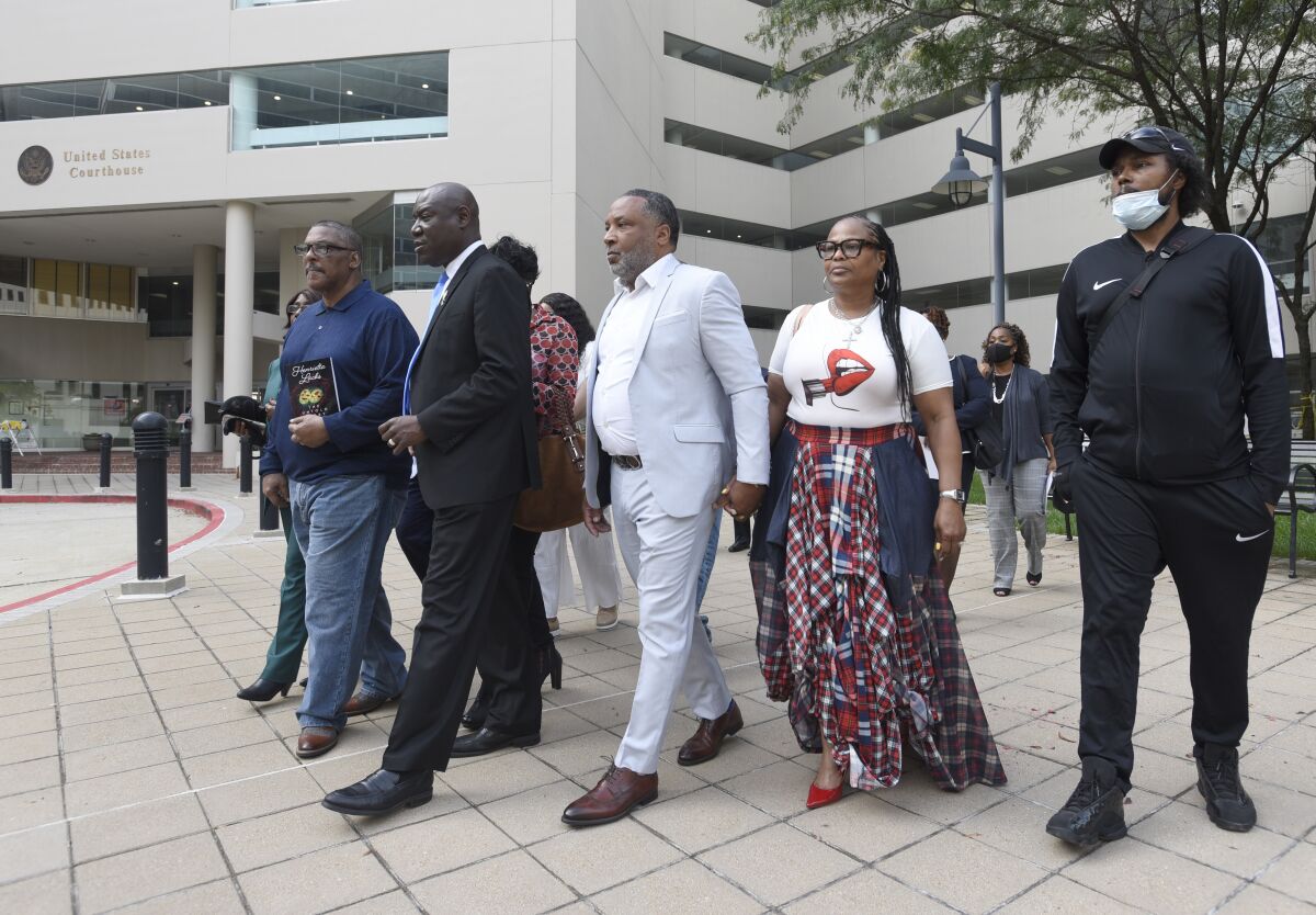 FILE - Attorney Ben Crump, second from left, walks with Ron Lacks, left, Alfred Lacks Carter, third from left, both grandsons of Henrietta Lacks, and other descendants of Lacks, outside the federal courthouse in Baltimore, Oct. 4, 2021. The family of Henrietta Lacks is settling a lawsuit against a biotechnology company it accuses of improperly profiting from her cells. Their federal lawsuit in Baltimore claimed Thermo Fisher Scientific has made billions from tissue taken without the Black womans consent from her cervical cancer tumor. (AP Photo/Steve Ruark, file)