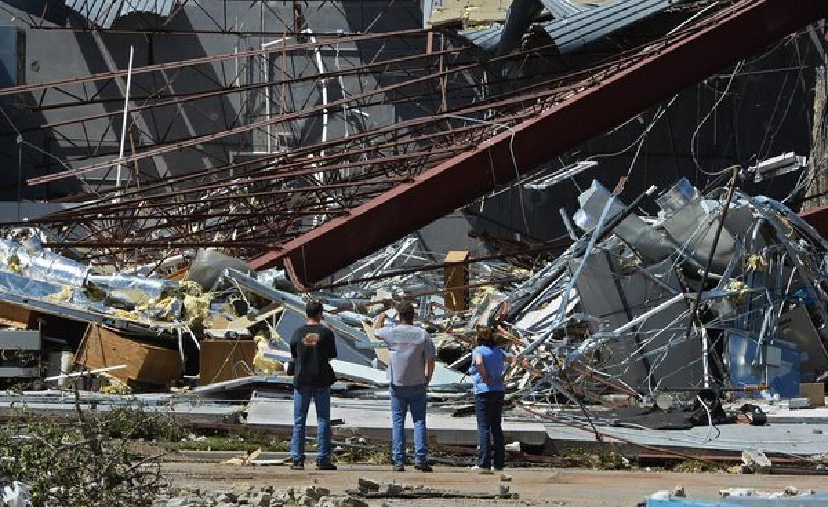 Bystanders look at a crumbled building at a technology school in El Reno, Okla., after a series of tornadoes hit the area. At least nine people were killed and more than 100 injured.