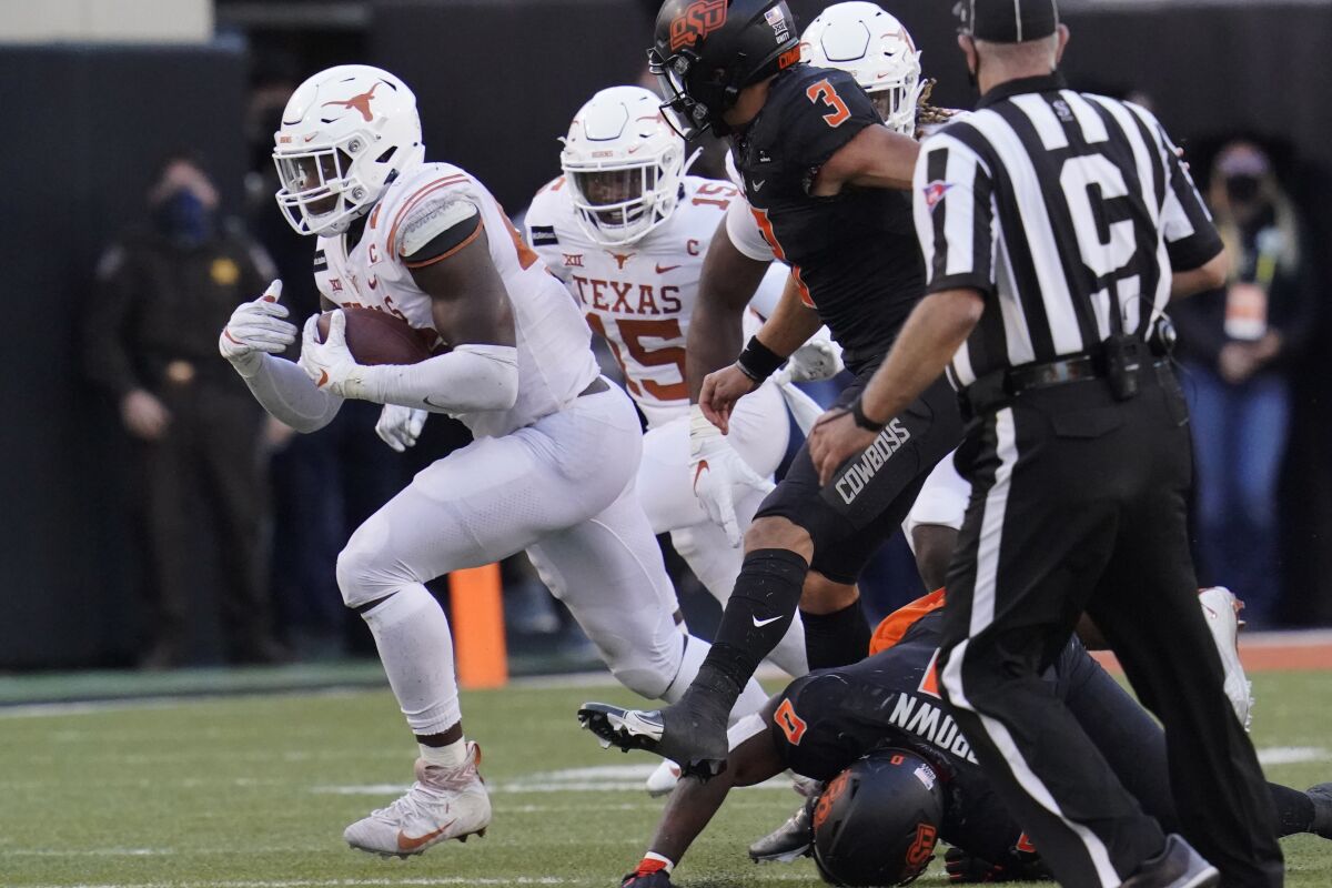 Texas's Joseph Ossai, left, carries a the ball after recovering an Oklahoma State fumble in the second half of an NCAA college football game in Stillwater, Okla., Saturday, Oct. 31, 2020. (AP Photo/Sue Ogrocki)