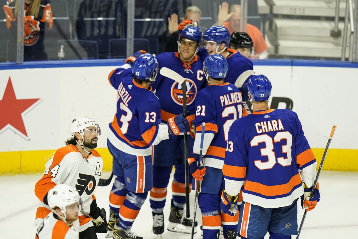 Philadelphia Flyers' Nate Thomposon skates past New York Islanders' Anders Lee as he celebrates with teammates after scoring a goal during the first period of a NHL preseason hockey game Tuesday, Oct. 5, 2021, in Bridgeport, Conn. (AP Photo/Frank Franklin II)