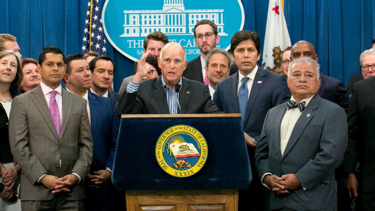 Gov. Jerry Brown, center, flanked by lawmakers from both sides of the aisle, speaks of the passage of a pair of climate change measures July 17 in Sacramento.