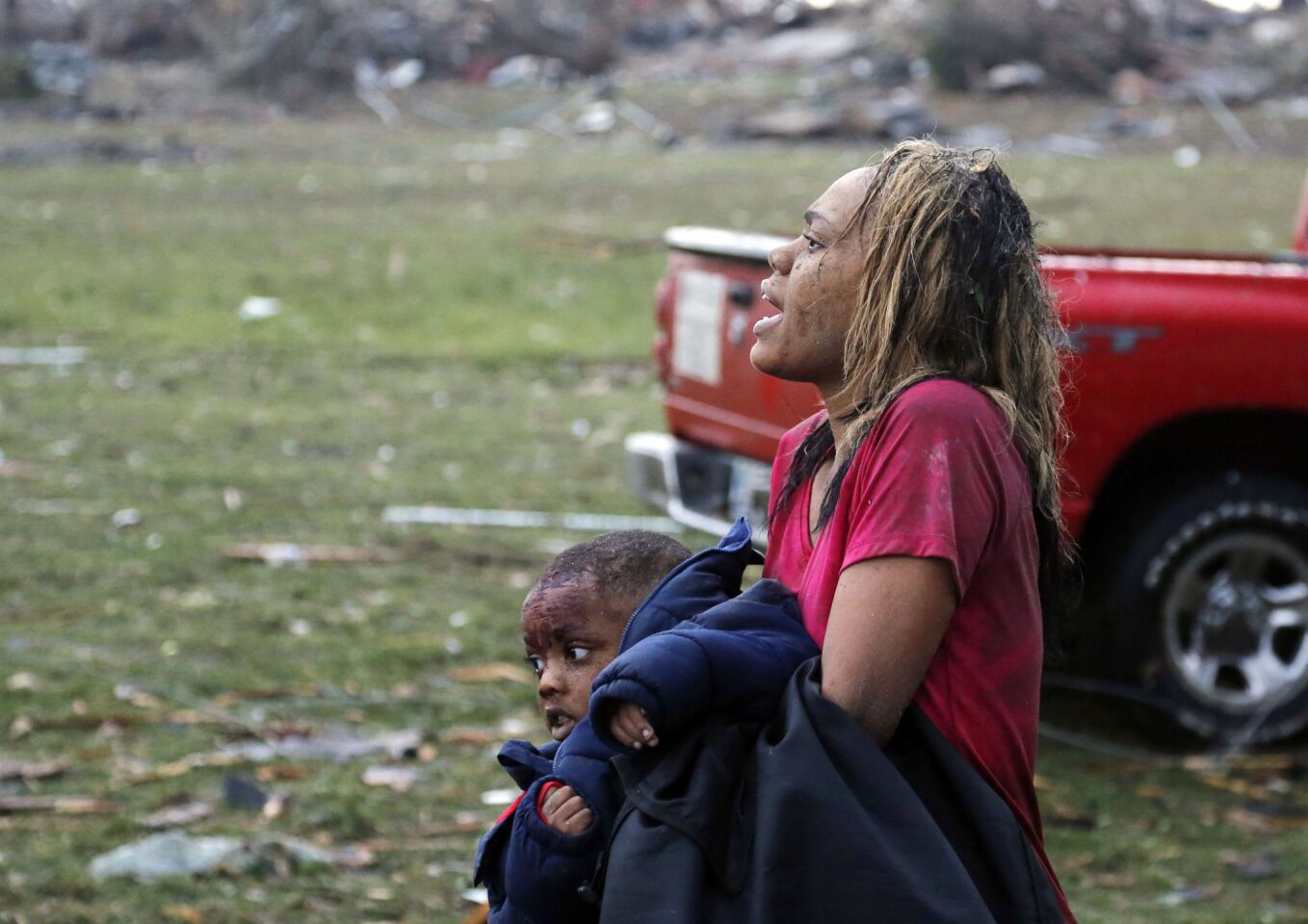 A woman carries an injured child to a triage center near the Plaza Towers Elementary School in Moore, Okla.