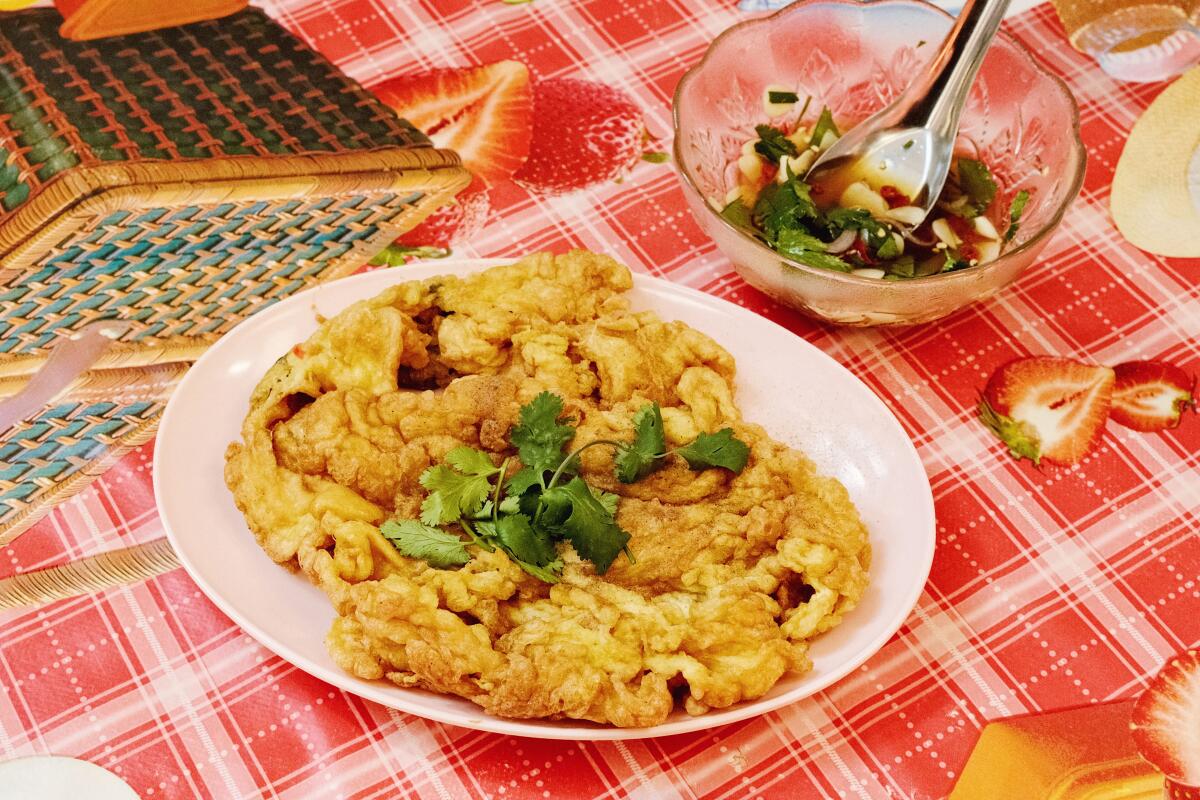 Une assiette rose posée sur une nappe à carreaux rouge contient une omelette.