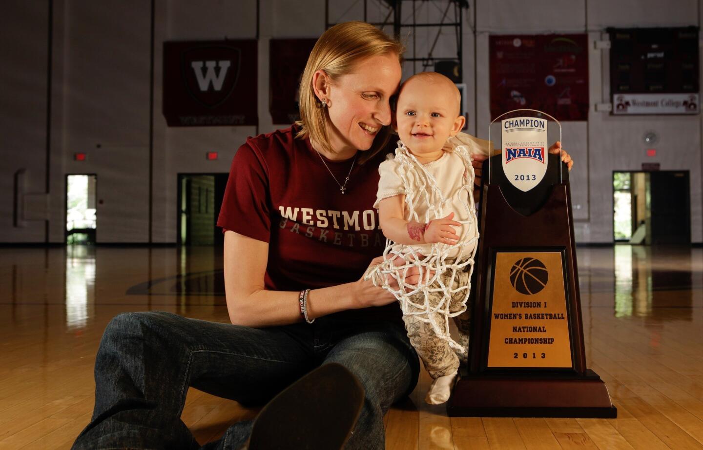 Kirsten Moore, women's basketball coach at Westmont College in Montecito, and daughter Alexis -- wearing the net that was cut down after the title game -- pose next to the 2013 NAIA championship trophy in the school's gym.