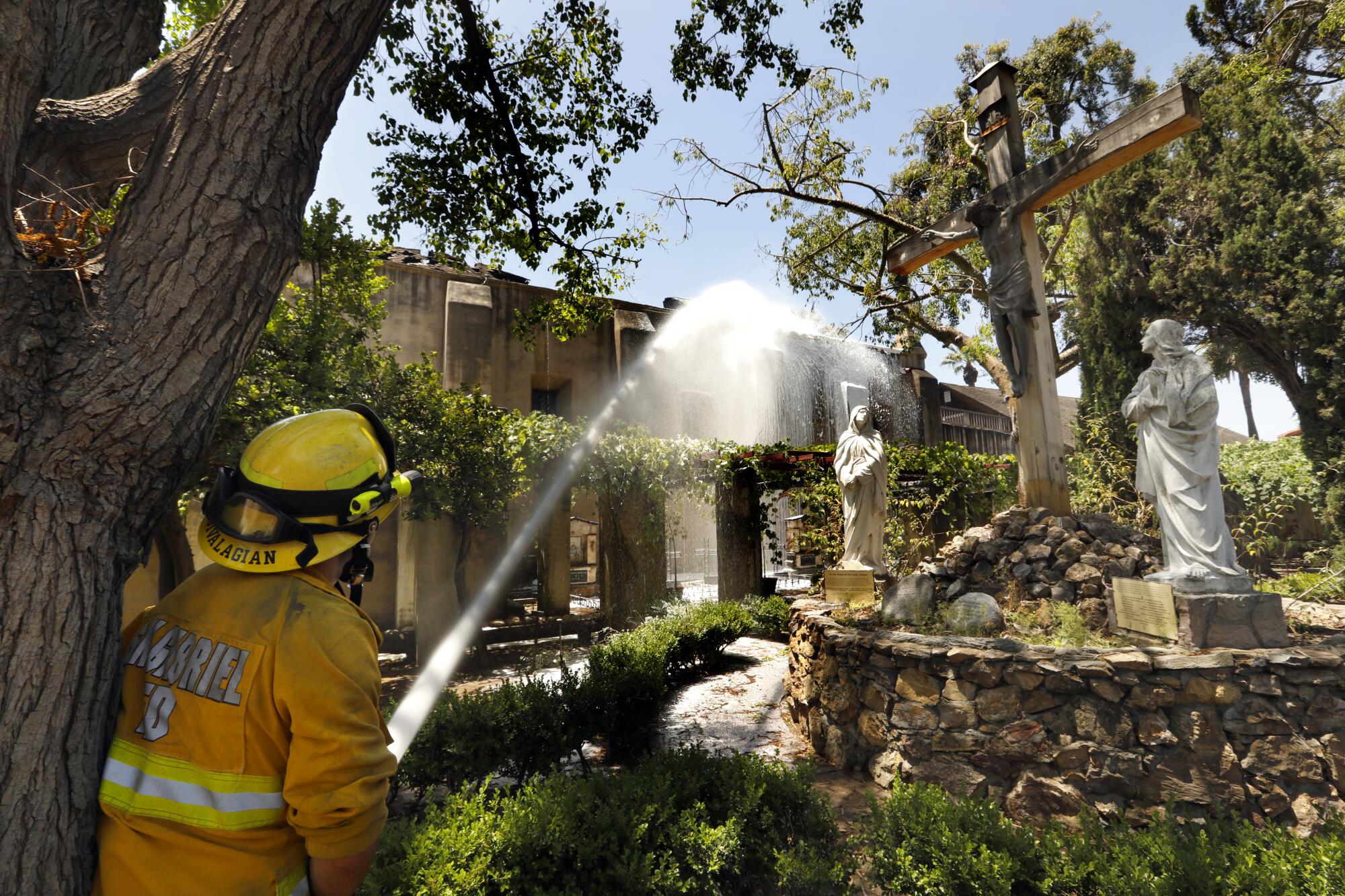 San Gabriel Firefighter Hrag Jivalagian uses a hose to spray down hot spots on the severely damaged San Gabriel Mission