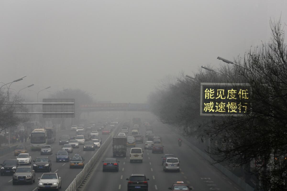 Vehicles drive along a road with a traffic sign reading "Visibility low, slow down the speed" on Monday, the latest in a series of heavily polluted days in Beijing.